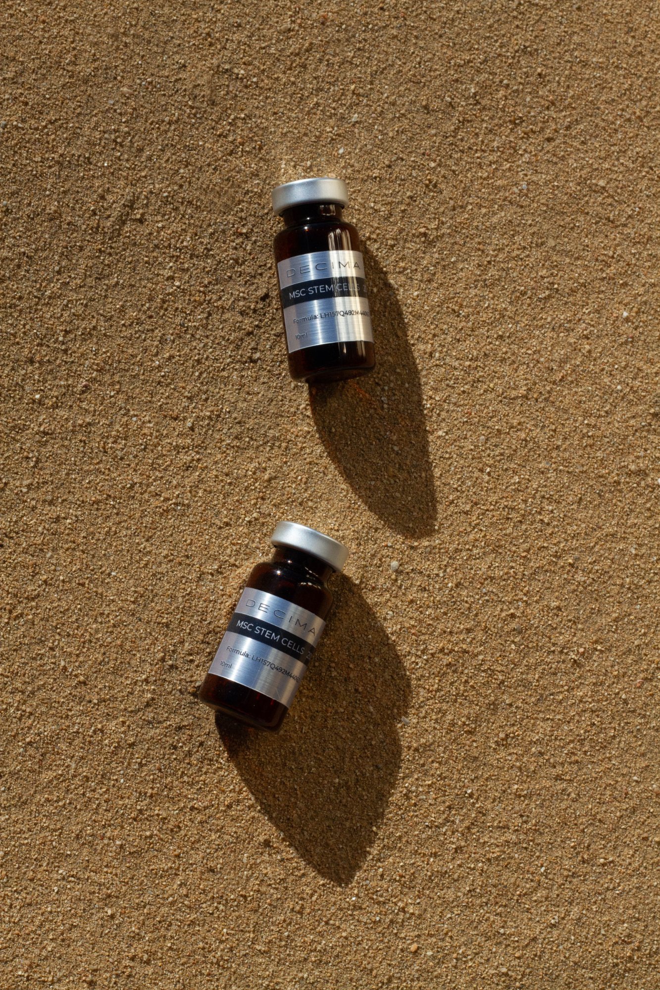 Two Decima vials on sand